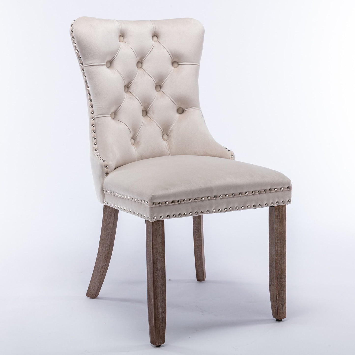 The Nikki set includes two modern, high-end velvet upholstered dining chairs with tufted backs, nailhead trim, and solid wood legs, shown against a plain white background.
