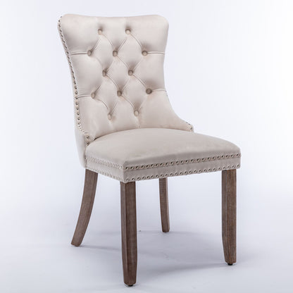 The Nikki set includes two modern, high-end velvet upholstered dining chairs with tufted backs, nailhead trim, and solid wood legs, shown against a plain white background.