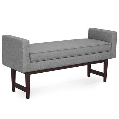 The Scott - Upholstered Ottoman Bench features a cushioned seat in light gray fabric, short armrests on each side, and dark wooden legs for a modern look.