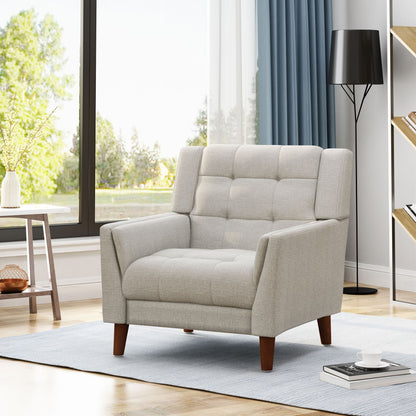 The Luminaesque Fabric Upholstered Armchair with a tufted back and wooden legs sits on a light blue rug in a bright living room with large windows, a side table with a plant, floor lamp, and bookshelves in the background.