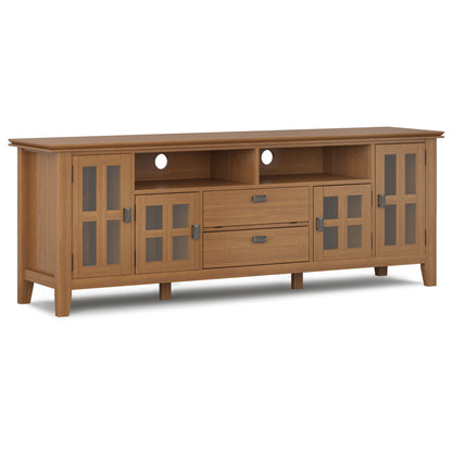 The Artisan TV Media Stand features a light brown wood finish, two glass-paneled side cabinets, two center drawers, an open shelf, and cable management holes at the back.