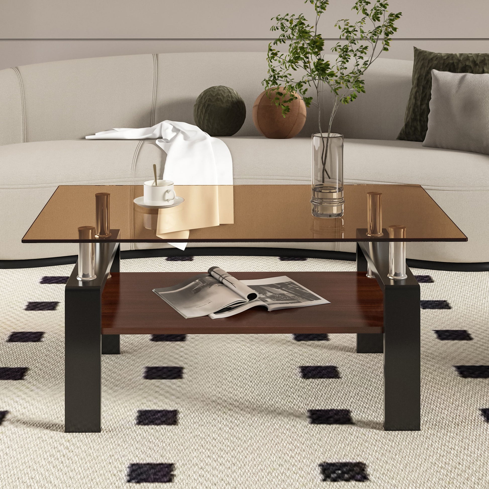A modern living room features the Modern Rectangular Coffee Table With Tempered Glass Top, displaying a vase with green branches, a cup and saucer, and a white cloth. An open magazine rests on the wooden shelf below; a sofa with pillows is behind.