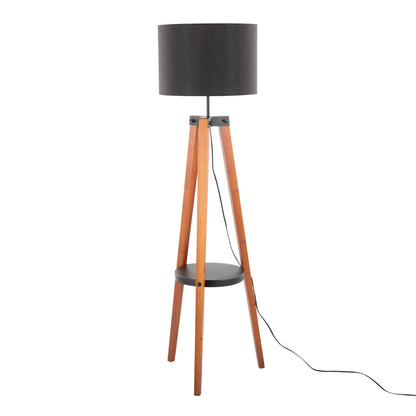 The Compass Mid Century Modern Floor Lamp features a black cylindrical shade, wooden tripod legs, a small round black shelf, and a visible black power cord.
