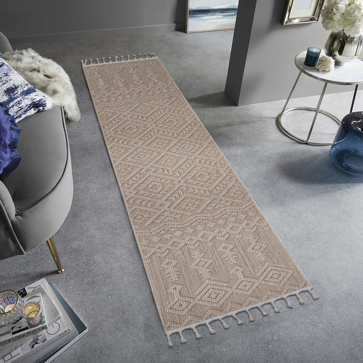 The Guros - Traditional Indoor / Outdoor Area Rug, a long beige runner with geometric patterns and fringed ends, decorates a light gray floor in a modern living room with contemporary furniture.