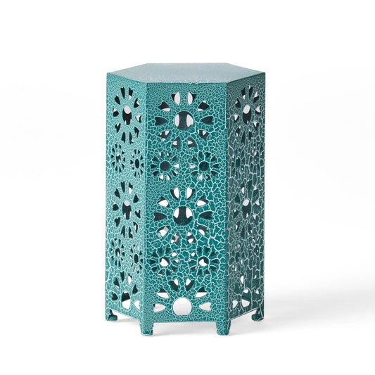 The Eliana Side Table features a hexagonal shape in teal with intricate cutout floral patterns and a textured finish, offering both decorative style and sturdy construction.