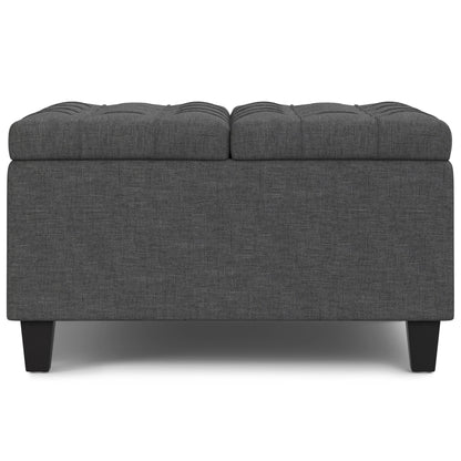 The Harrison Upholstered Coffee Table Storage Ottoman is rectangular, dark gray with a tufted top and short black legs, pictured against a white background.