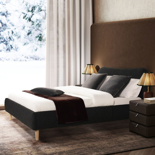 A modern bedroom featuring the Roman - Curved Headboard Upholstered Platform Bed, dressed in white bedding with gray and black pillows, two bedside tables with lamps, and a large window overlooking a snowy landscape.