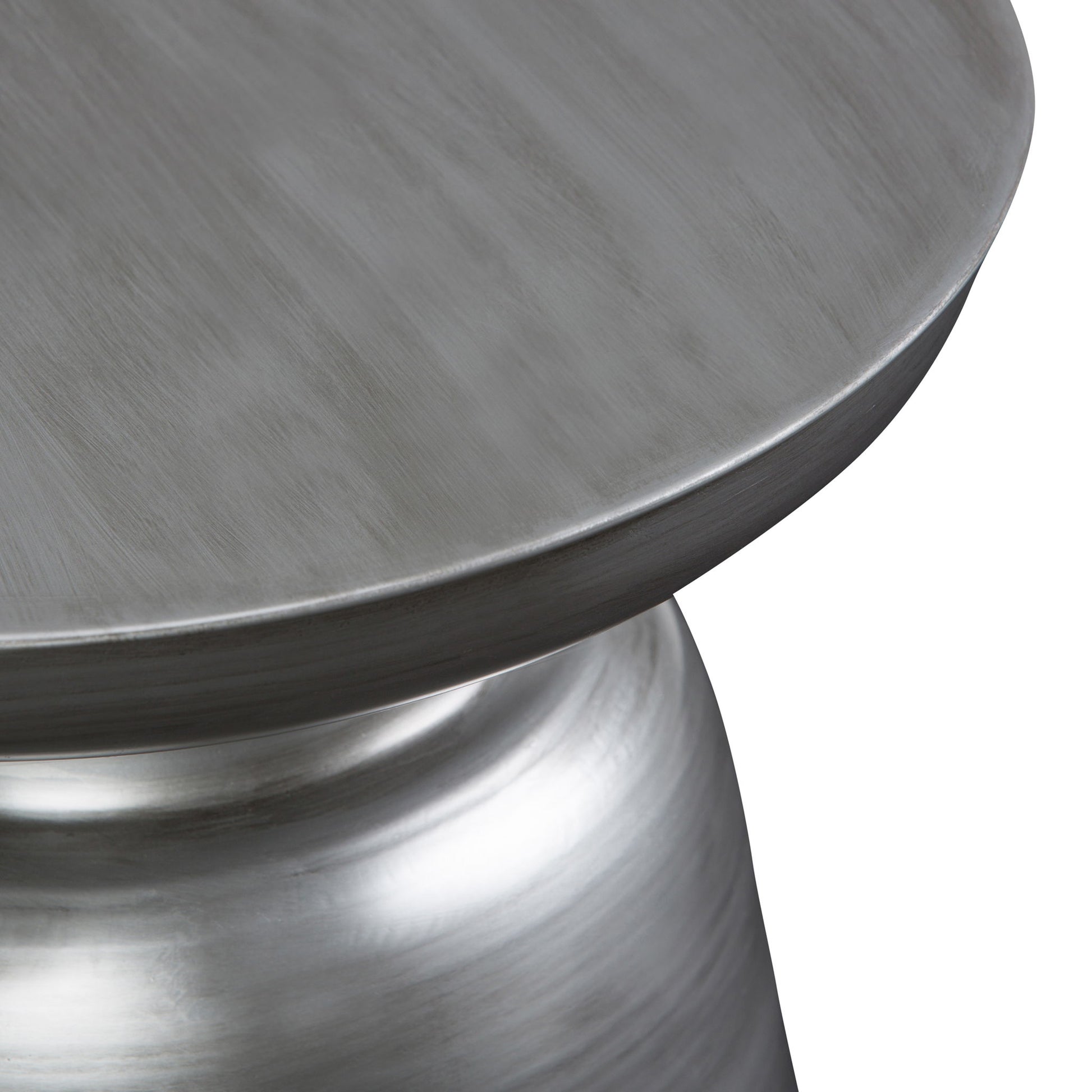Close-up of the Toby - Handcrafted Metal Accent Table, featuring a round, metallic silver top with a smooth, brushed finish and a curving pedestal base. Set against a plain white background.