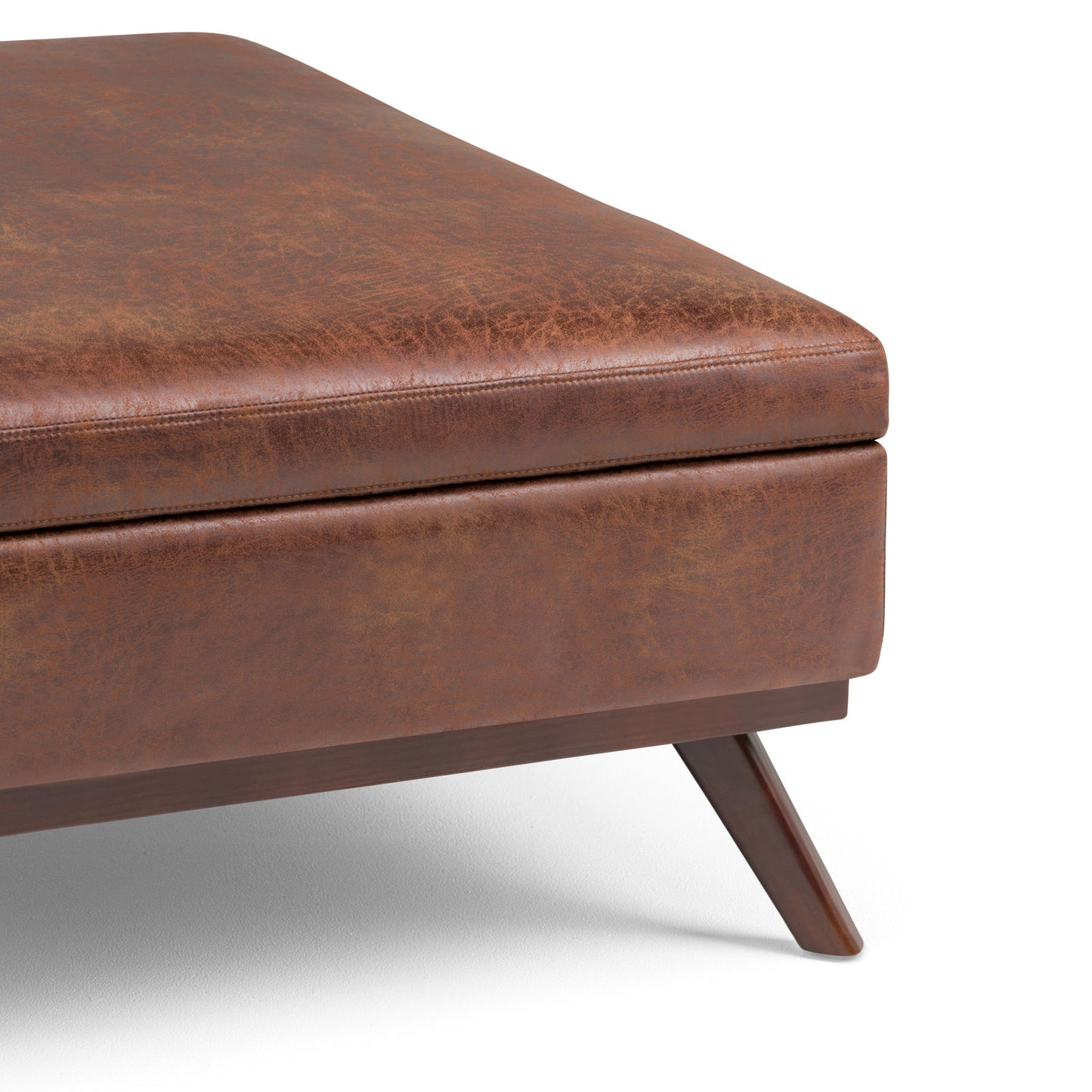 Close-up of the Owen Multifunctional Square Coffee Table Storage Ottoman in brown leather with angled wooden legs and visible stitching, displayed on a white background.