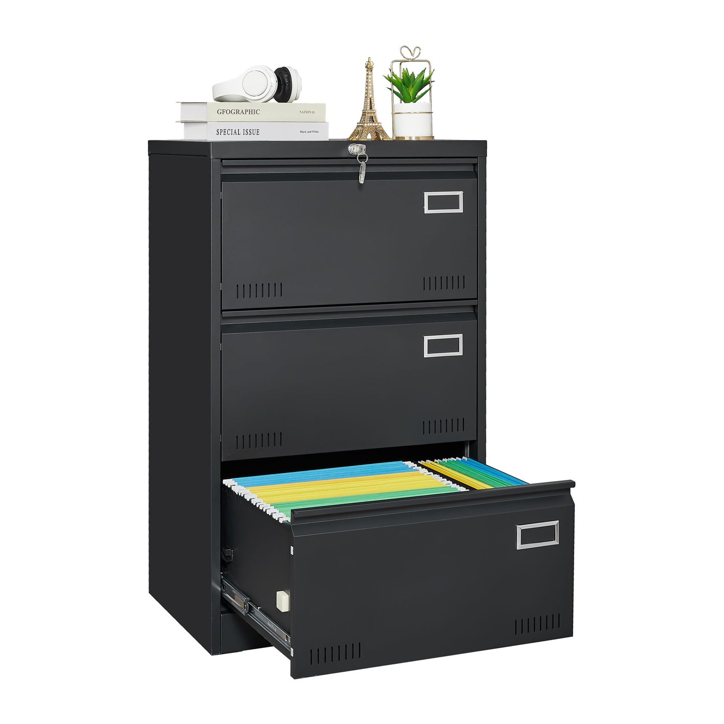 The Filing Cabinet Lateral File Cabinet 3 Drawer is a black metal cabinet with a locking system; its bottom drawer is open revealing colorful file folders, while the top holds books, a camera, an Eiffel Tower figurine, and a potted plant.