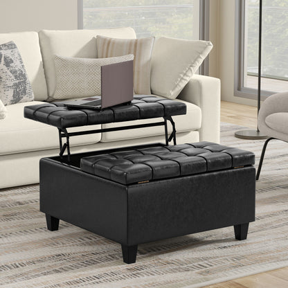 The Harrison Large Coffee Table Storage Ottoman, featuring a black tufted design and lift-top tray with a laptop, rests on a striped rug before a beige sofa with patterned cushions in a modern living room.