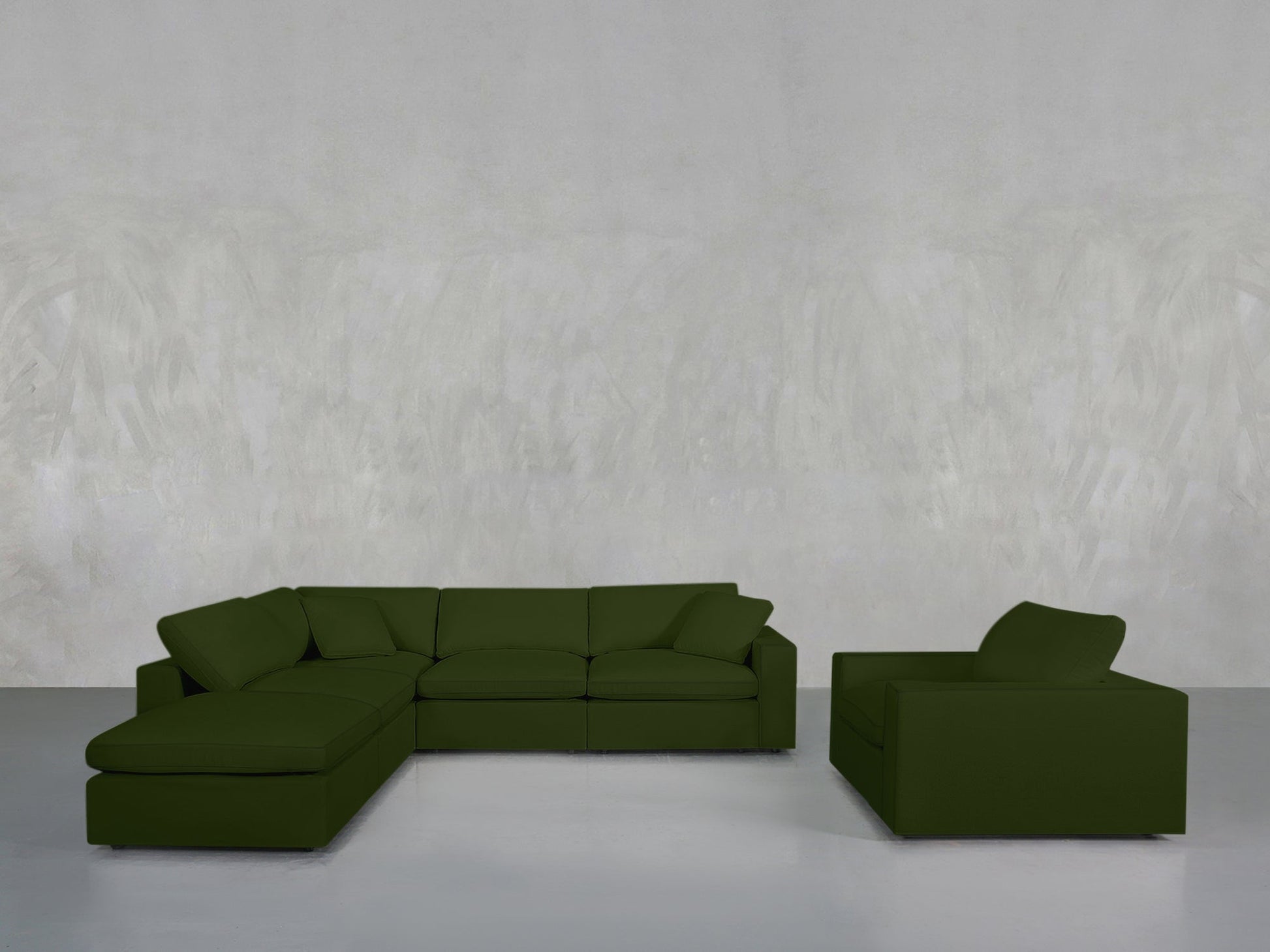 The 5-1 Sectional & Armchair Set in olive green, featuring an attached chaise, rests on a light gray floor beside its matching armchair, all set against a plain textured light gray wall.