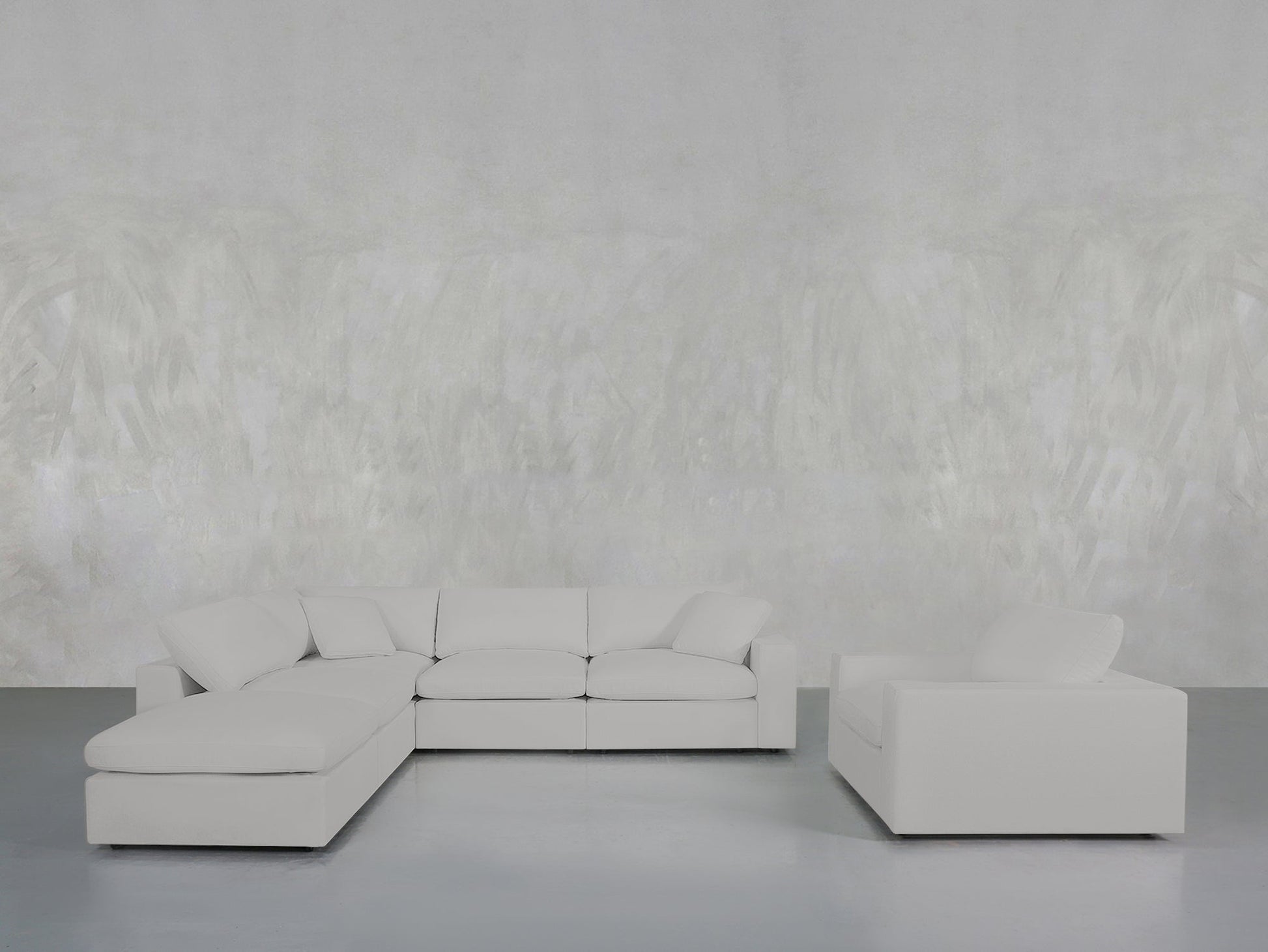 A minimalist living room featuring the 5-1 Sectional & Armchair Set in light gray, placed against a pale textured wall and smooth gray floor.