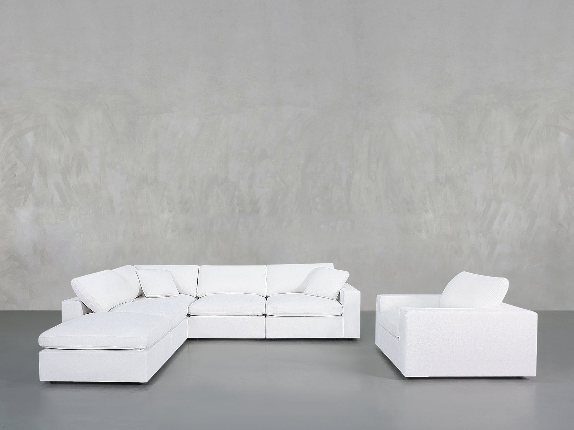 A minimalist living room with the 5-1 Sectional & Armchair Set in white, set against a light gray textured wall and a smooth gray floor.