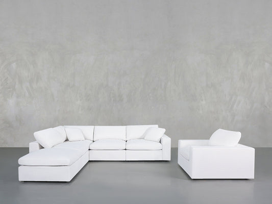 A minimalist living room with the 5-1 Sectional & Armchair Set in white, set against a light gray textured wall and a smooth gray floor.