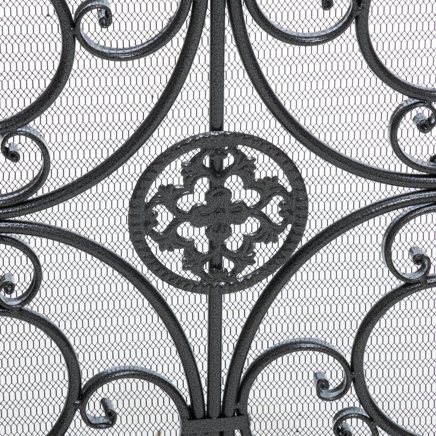 Close-up of the Darcie Wrought Fireplace Screen showcasing an ornate circular floral centerpiece with swirling curves and symmetrical details, set against a fine metal mesh background.