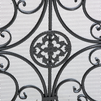 Close-up of the Darcie Wrought Fireplace Screen showcasing an ornate circular floral centerpiece with swirling curves and symmetrical details, set against a fine metal mesh background.