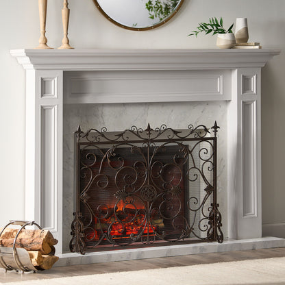 A white fireplace features the Darcie - Wrought Fireplace Screen with an ornate design, glowing embers inside, a round mirror and candles on the mantel, and a log holder with firewood beside it.