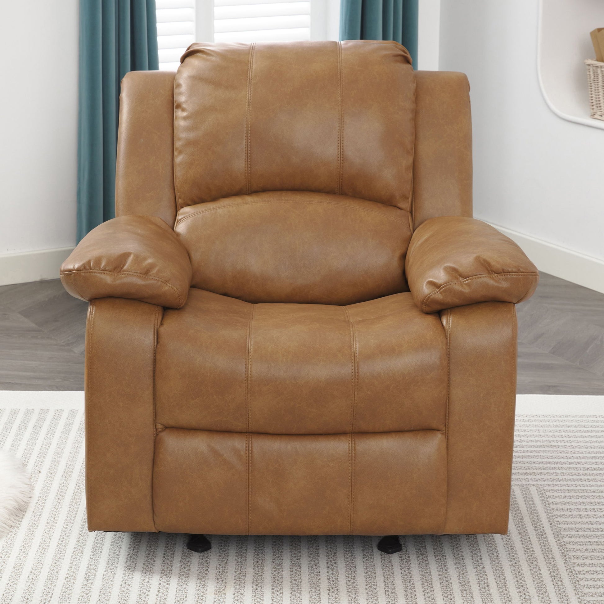The Charlotte Glider Recliner With Classic Style, featuring plush cushions and wide armrests, sits on a light striped rug in a modern living room with blue curtains and a white wall in the background.