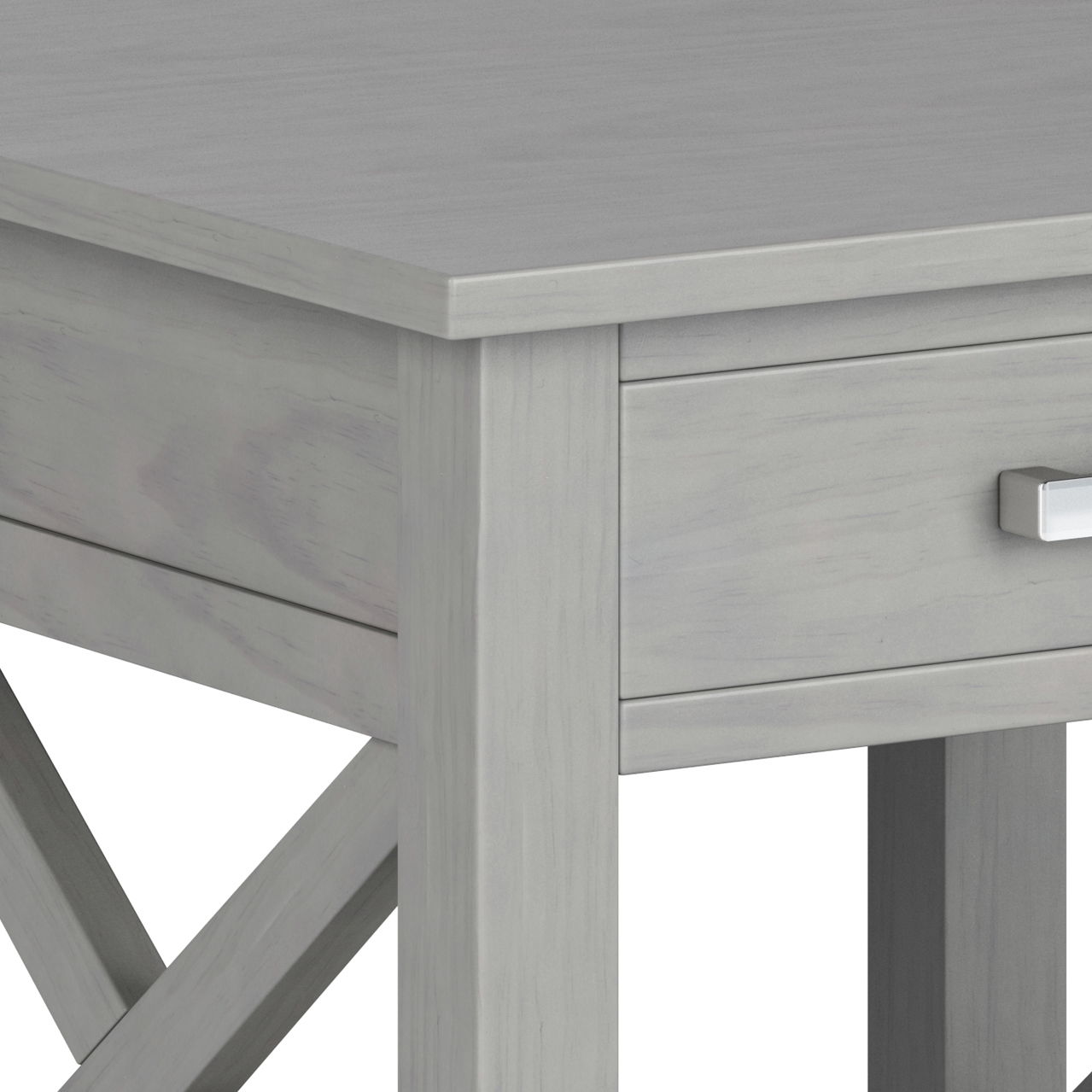 Close-up of the Kitchener - Handcrafted Table in light gray, highlighting the corner, a drawer with a rectangular silver handle, and X-shaped cross-brace legs.