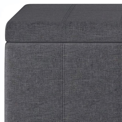Close-up of the Dover Upholstered Storage Ottoman Bench in gray, featuring a rectangular shape, cushioned lid, subtle textured fabric, and stitched seam detailing.