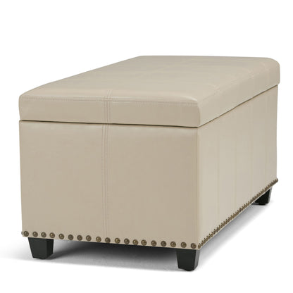 The Amelia Transitional Storage Ottoman Bench features a rectangular beige upholstered design, cushioned top, decorative stitching, nailhead trim along the base, and short black legs.