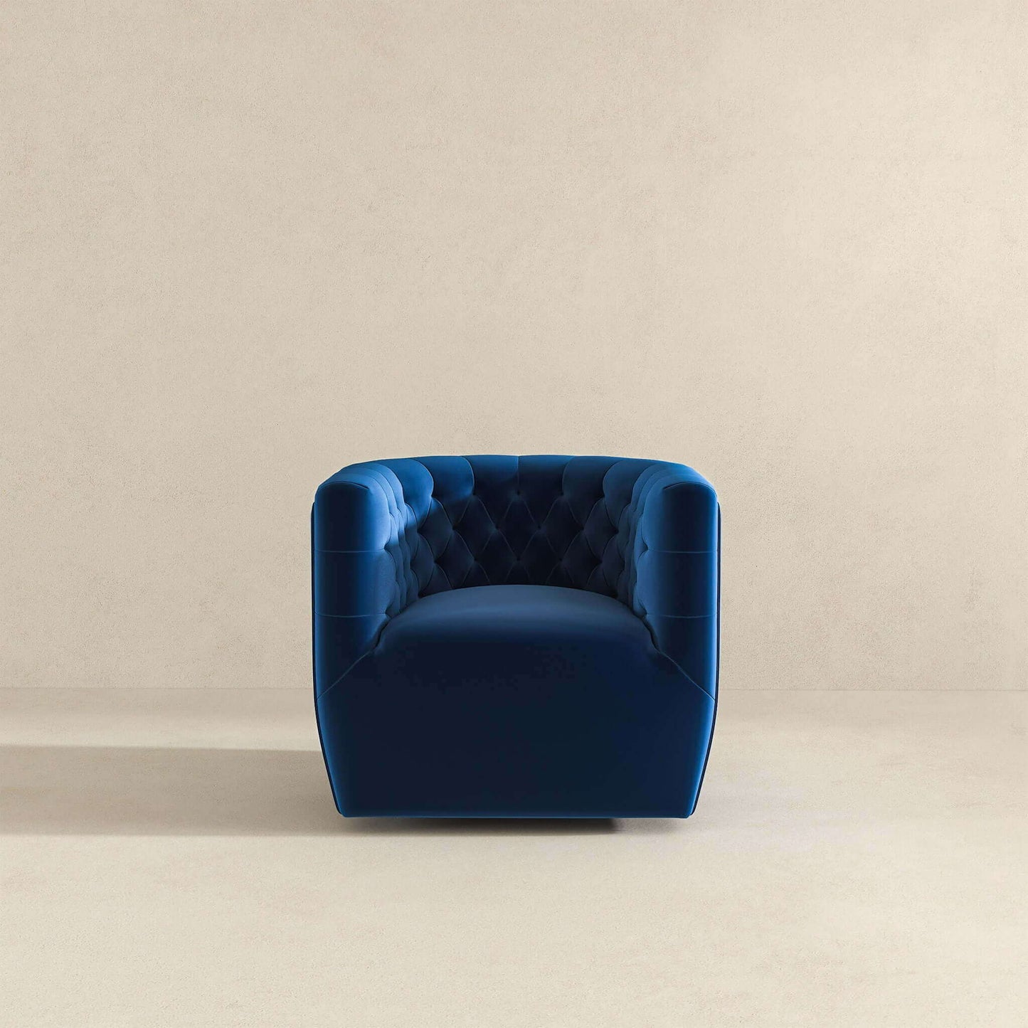 The Delaney Ergonomic Design Swivel Chair, in deep blue velvet with tufted upholstery and square arms, is centered and faces forward against a plain light beige wall and floor.