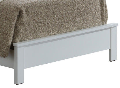 A close-up of the foot of the Bed With Transitional Design Stylish, featuring a white wooden frame and a thick beige textured blanket draped over it.