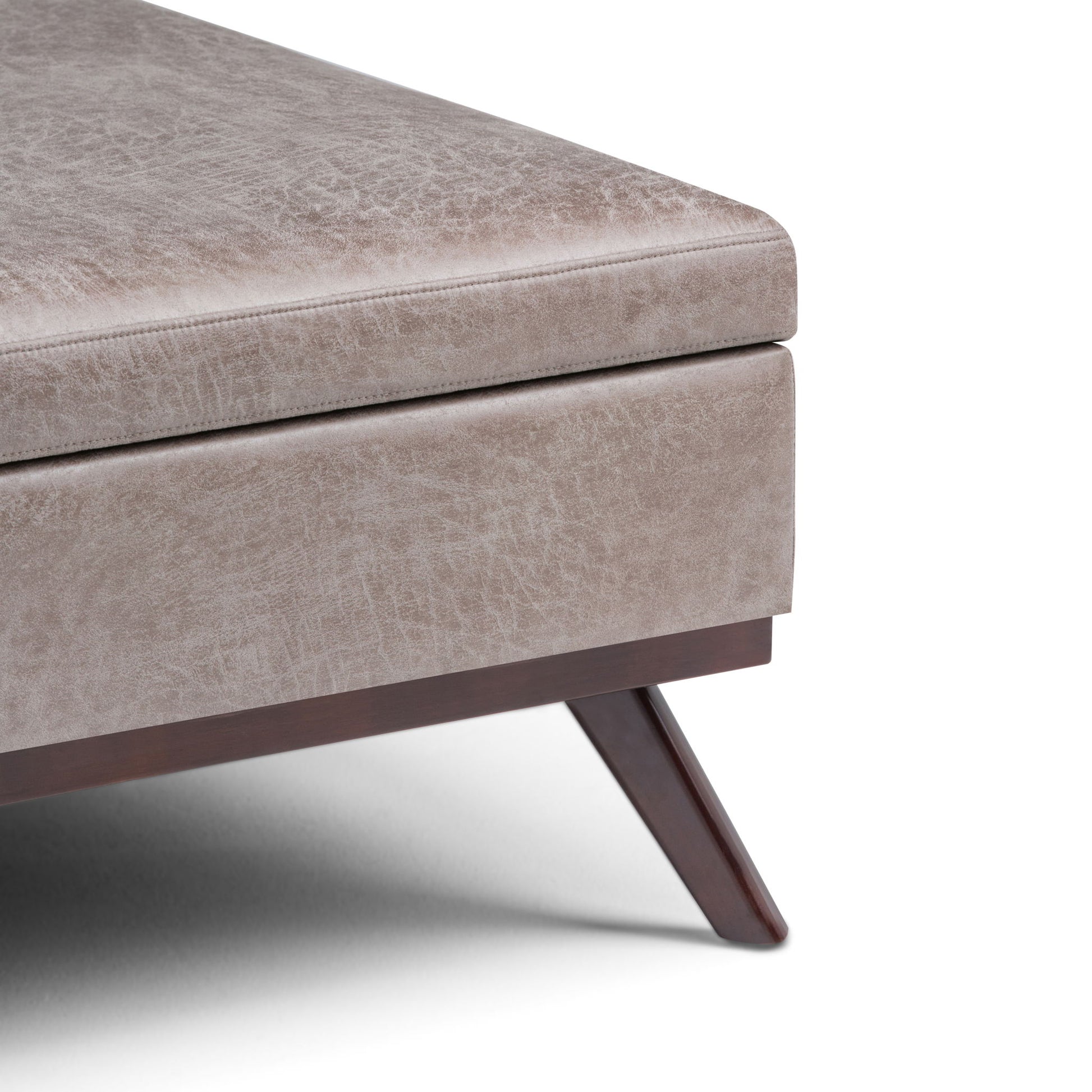 Close-up of the corner of the Owen - Multifunctional Square Coffee Table Storage Ottoman in beige, featuring textured upholstery, dark wooden legs, and a modern design.