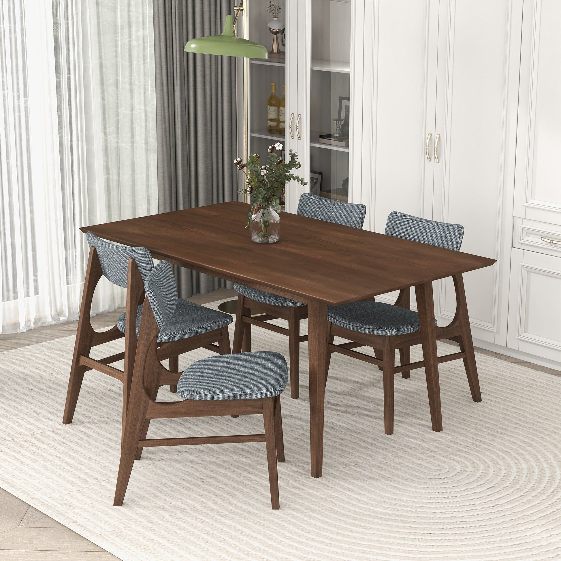 A modern dining room featuring the Levi Modern Style Rectangular Dining Kitchen Table, four blue-cushioned chairs, a floral vase centerpiece, white cabinets, grey curtains, a green pendant light above a light oval rug.