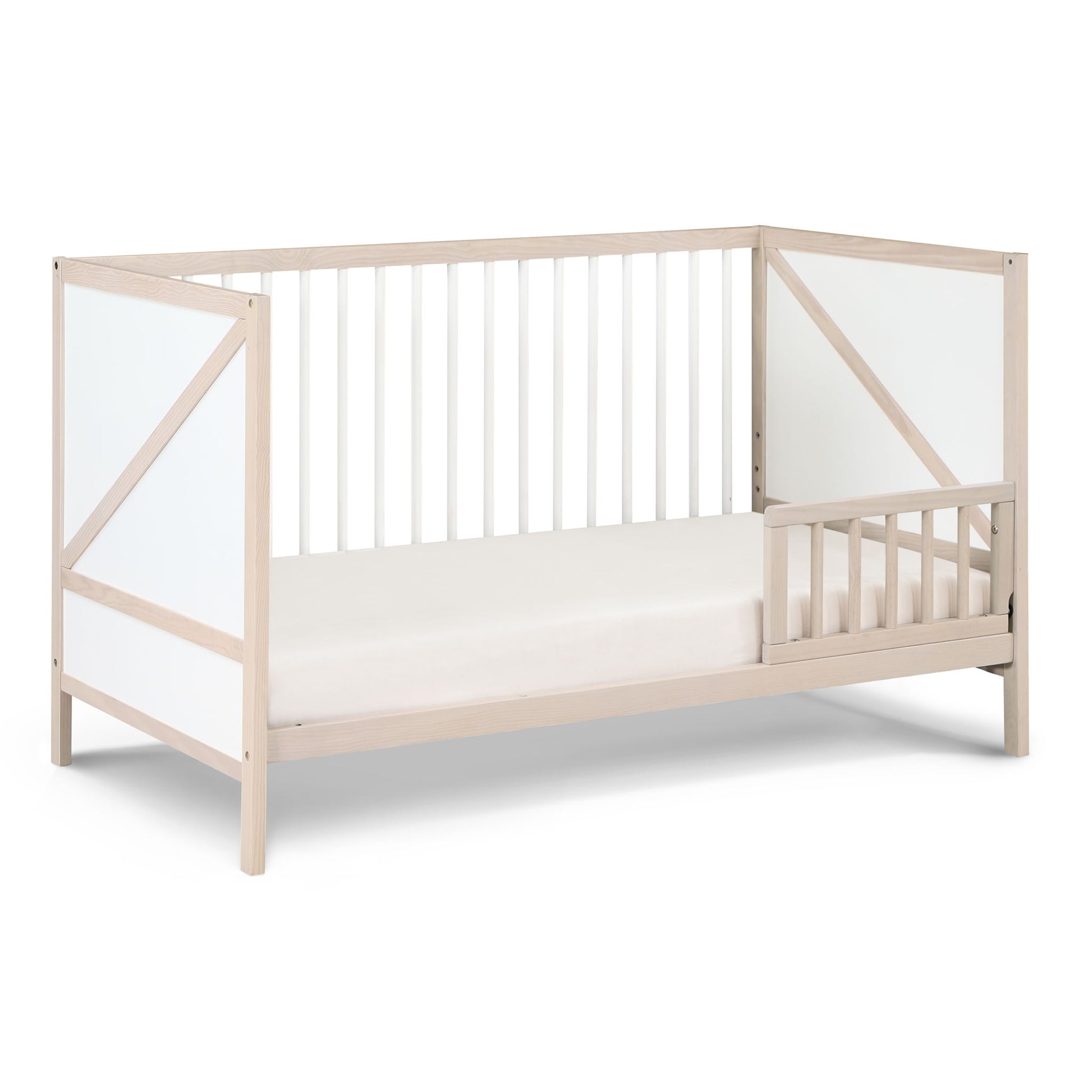 The Pixie Zen 3-in-1 Crib in Walnut features white panel accents, open slatted sides, and a partial safety rail on one side, displayed against a white background.