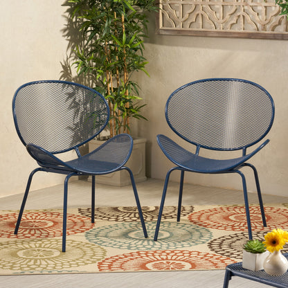 The Elba Contemporary Chair Set for Outdoor Relaxation features two modern blue metal chairs with mesh backs and seats, styled on a circular-patterned rug, with a small floral table, a green potted plant, and a decorative wall panel nearby.