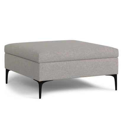 The Rebecca Multifunctional Coffee Table Storage Ottoman features a square, light gray upholstered design with a flat top, slim black metal legs, and a lift-up lid for storage. Shown on a white background.
