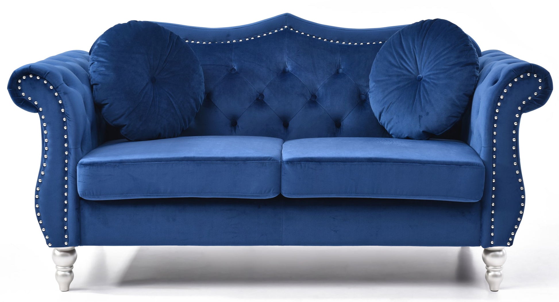 The Stylish Flared Arm Loveseat features plush royal blue velvet upholstery, tufted details, silver nailhead trim, two round pillows, curved armrests, and short silver legs.