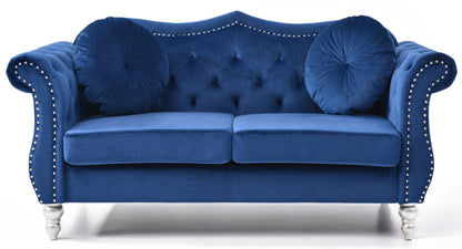 The Stylish Flared Arm Loveseat features plush royal blue velvet upholstery, tufted details, silver nailhead trim, two round pillows, curved armrests, and short silver legs.