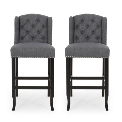 The Vienna - Contemporary Fabric Tufted Wingback Counter Stools (Set of 2) feature dark wooden legs, diamond-tufted gray fabric backs, and silver nailhead trim, shown side by side against a white background.