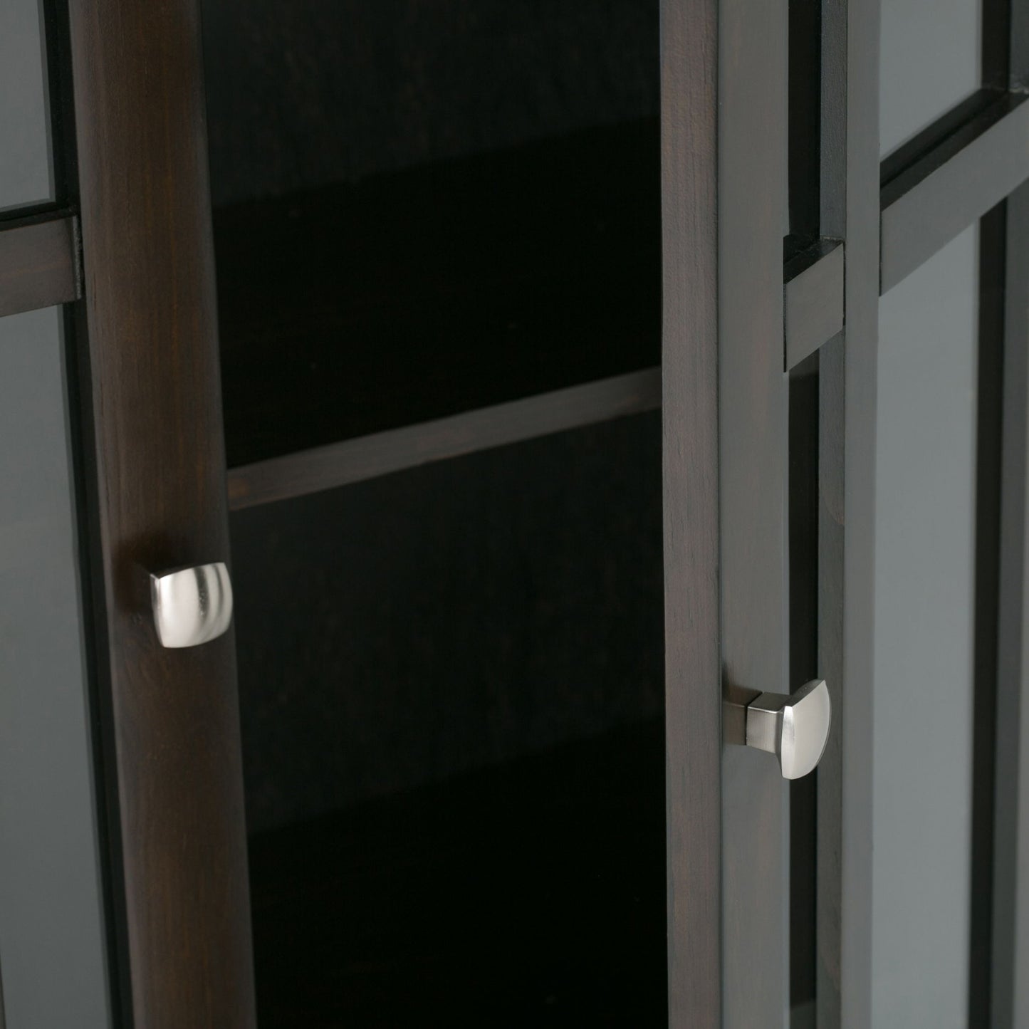 Close-up of the Bedford - Storage Media Cabinet, featuring dark wood, glass doors, silver square handles, and an empty interior shelf.