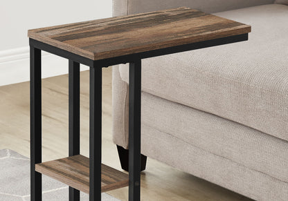 The Accent Table C - Shaped, Contemporary & Modern features a wood-grain top and lower shelf with a black metal frame, shown beside a light beige upholstered sofa on a hardwood floor.