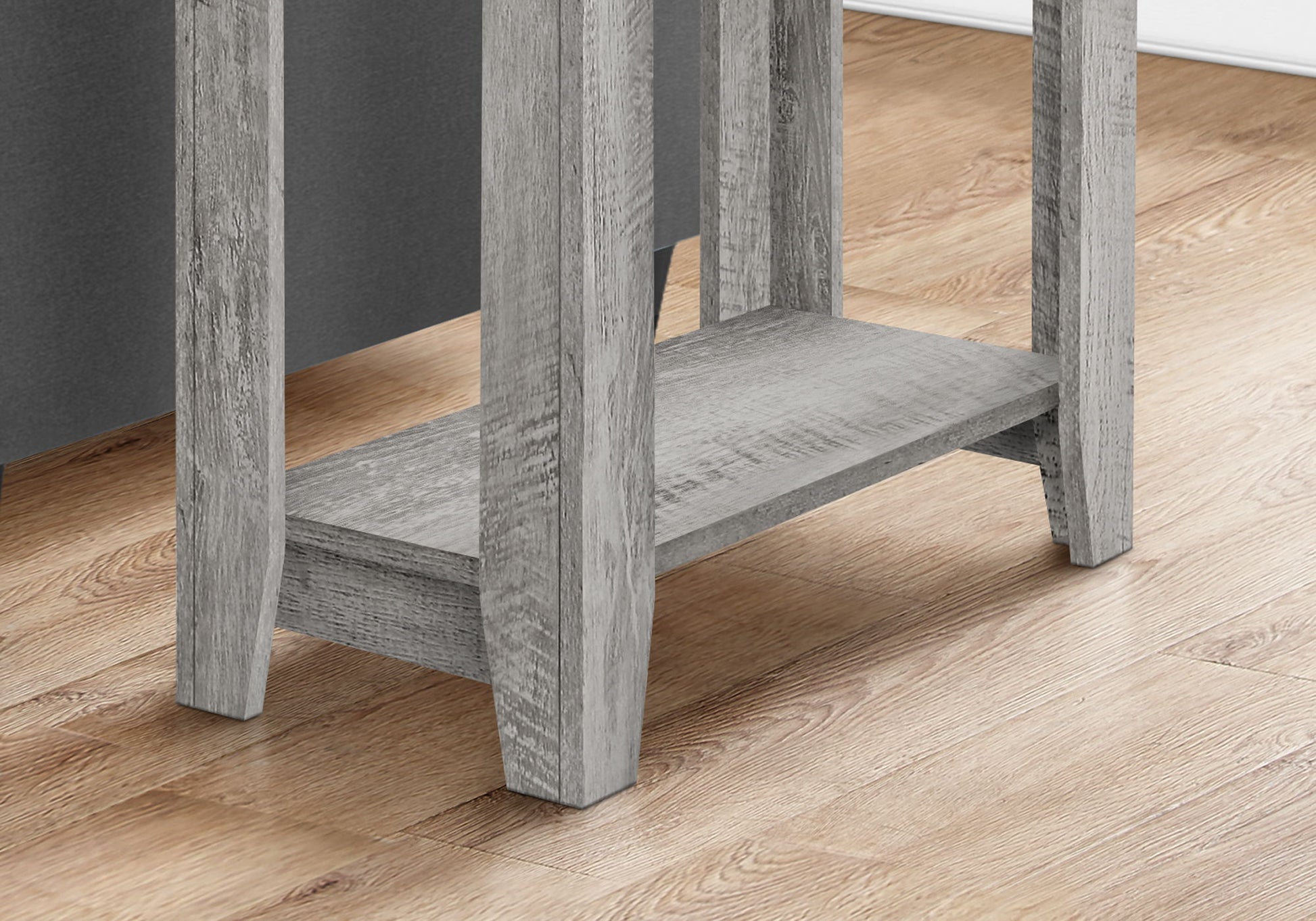 Close-up of the bottom part of the Accent Table, Side Transitional with an elegant design, featuring four legs and a lower shelf, shown on a light wood floor by a dark wall.