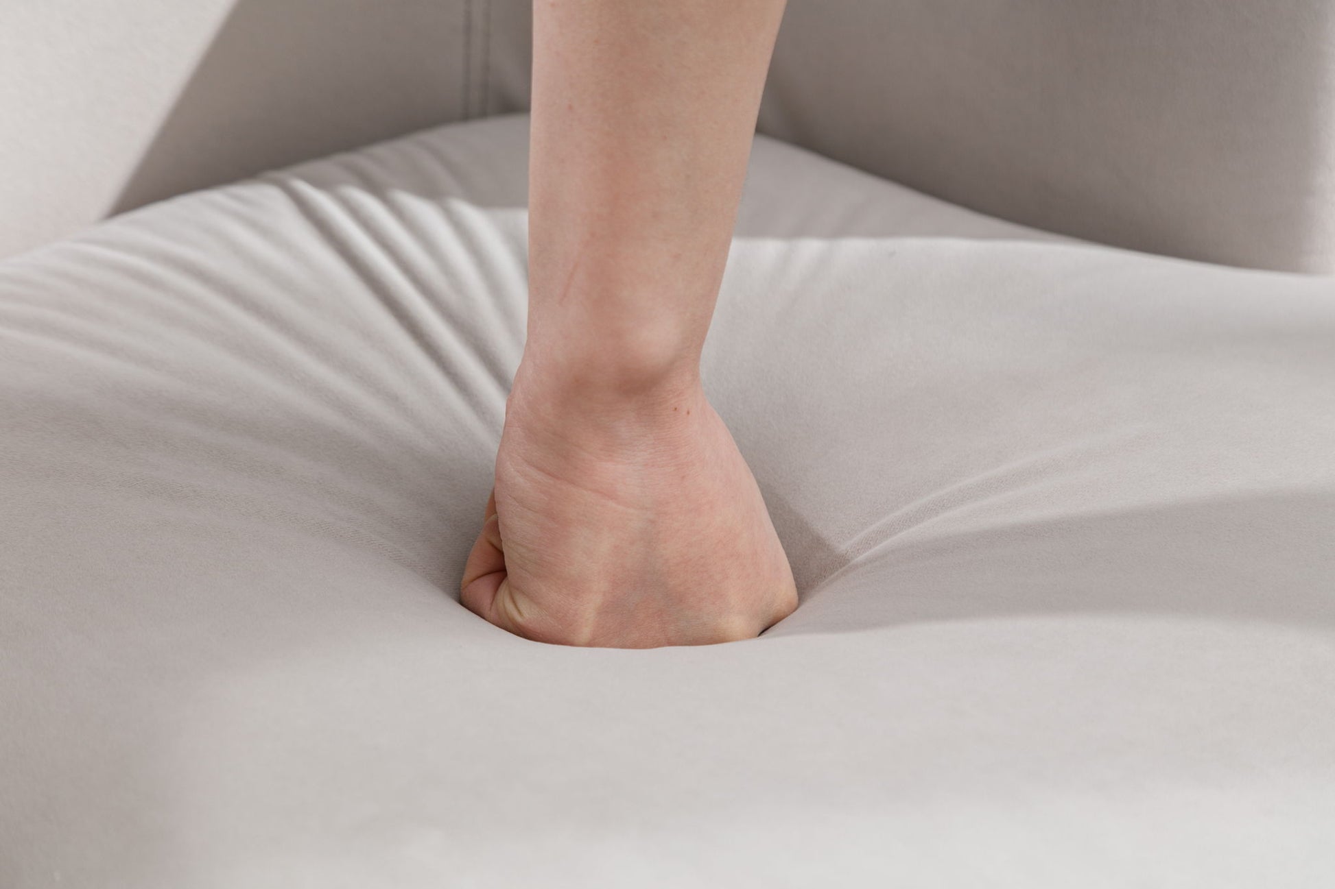 A hand presses into the soft, light gray velvet cushion of the Swivel Accent Armchair Barrel Chair, creating a deep indentation in the plush fabric.