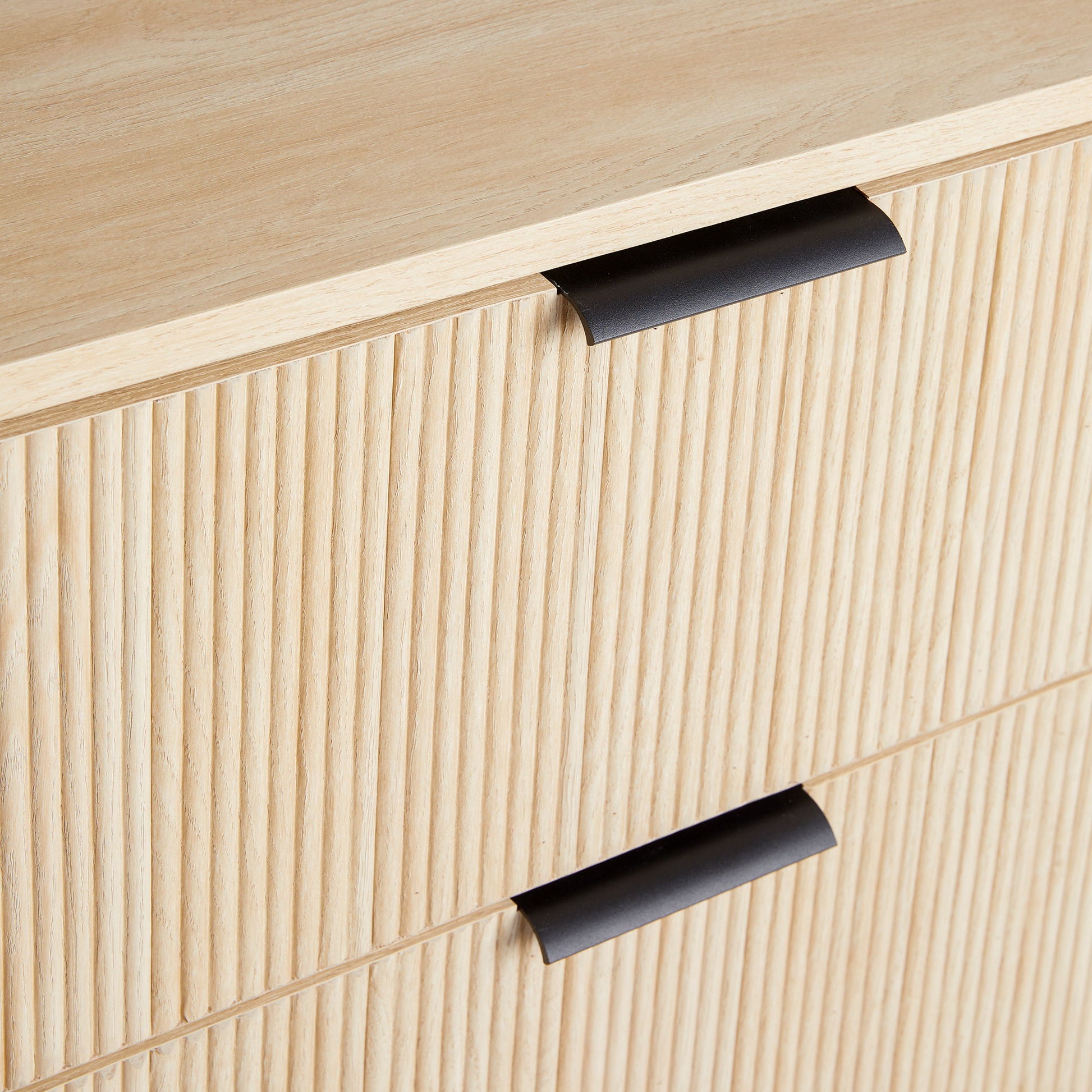 Close-up of the Mid-Century 3 Drawer Chest featuring reeded drawer fronts and modern black metal handles in light wood.