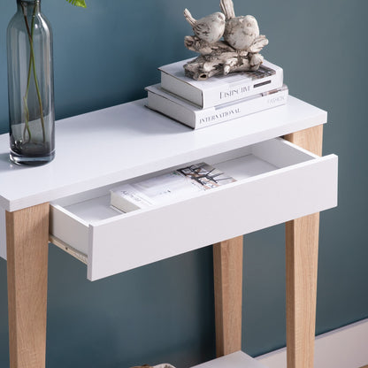 A Modern Two Toned Console With Two Shelves stands against a blue wall. One shelf has an open magazine; the top holds stacked books, a glass vase with a single stem, and a decorative two-bird sculpture.
