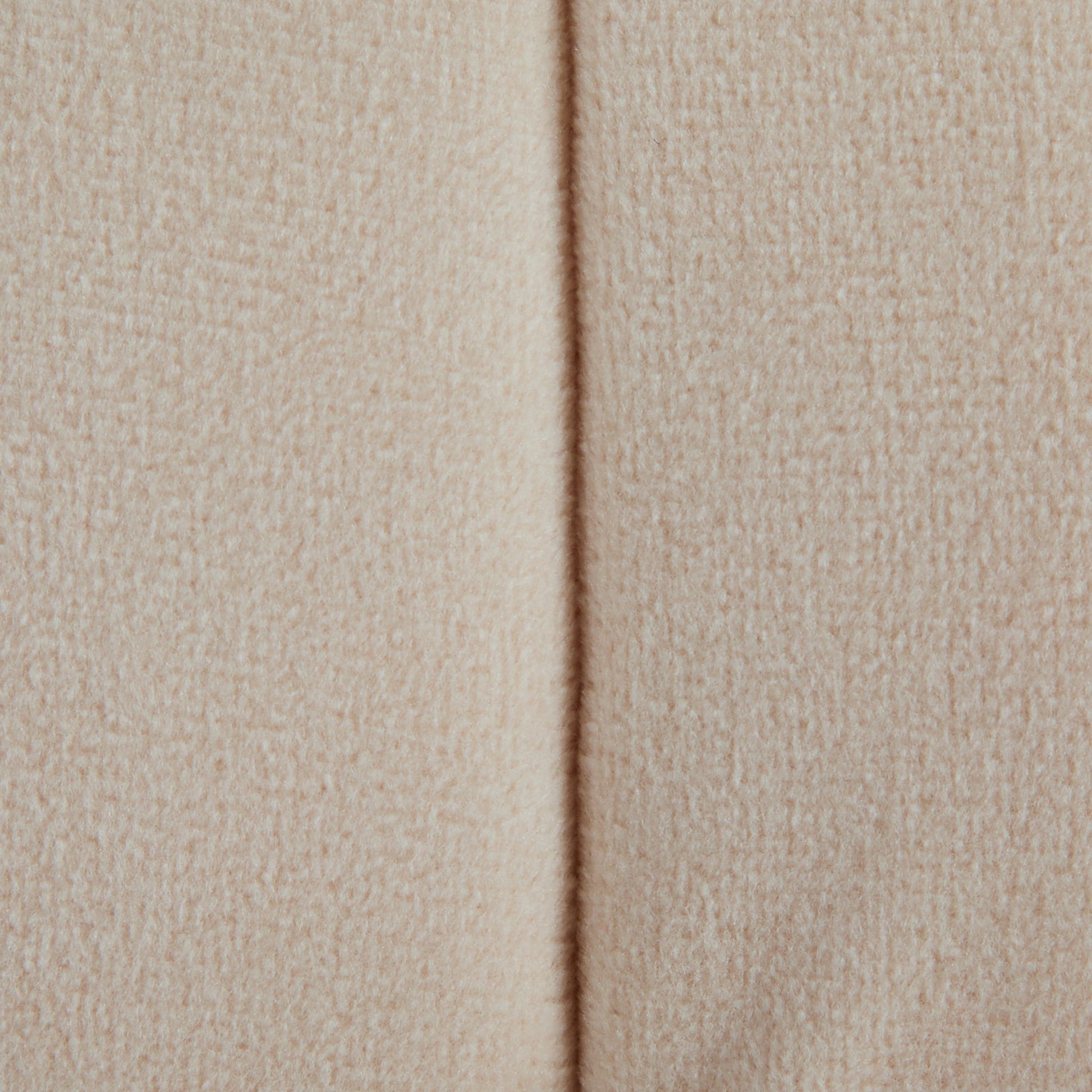Close-up of the Braided - Versatile Round Ottoman in beige, showing its textured fabric and a vertical center seam. The material looks soft and inviting, adding warmth and style to any space.