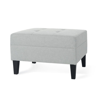 The Classic Ottoman features light gray fabric upholstery, a rectangular tufted top, and four black birch wood legs.