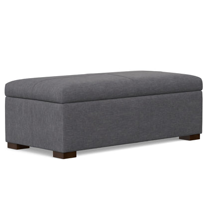 The Gabbie Coffee Table Upholstered Storage Ottoman is a large rectangular gray piece with a cushioned top and short wooden legs, shown against a white background.