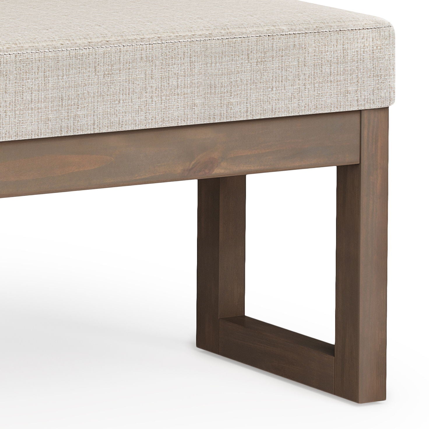 A close-up of the Milltown Upholstered Ottoman Bench shows its light beige cushion and dark brown wooden frame with rectangular, geometric legs.