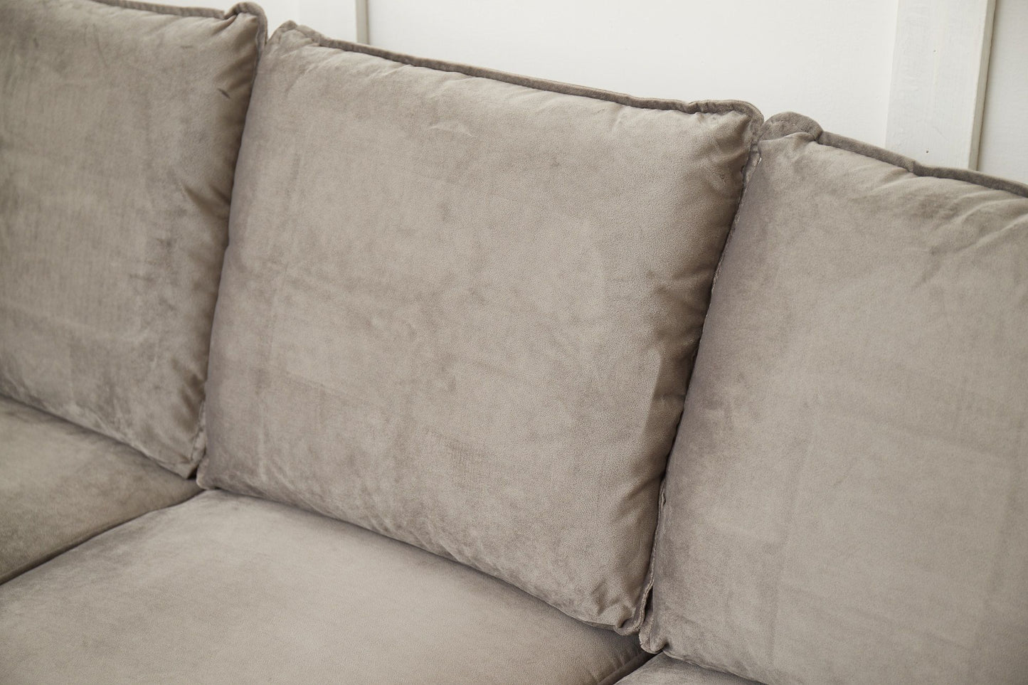 A close-up of the Graceful Design Plush Comfort Sofa highlights its three large, plush light gray back cushions with a subtle texture, set against a white wall.