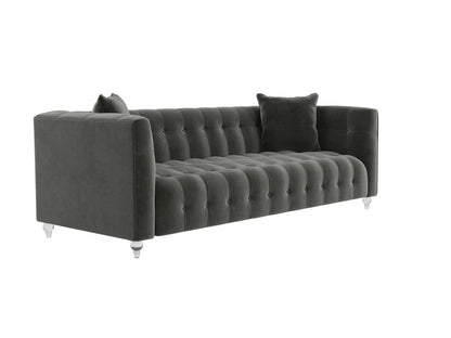 The Bea Velvet Tufted Sofa in dark green comes with two matching cushions and is supported by clear legs. This sofa boasts a modern design with a high back and armrests, offering a plush and elegant appearance.