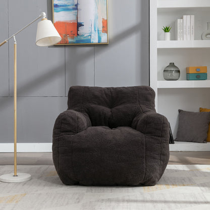A Soft Teddy Fabric Tufted Foam Bean Bag Chair sits on a light rug in a modern living room with gray walls, a floor lamp, colorful abstract art, and white shelves holding books and decor.