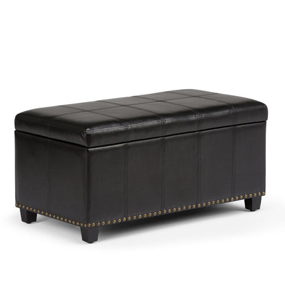 The Amelia - Transitional Storage Ottoman Bench is a rectangular black leather ottoman with stitched detailing, four short legs, and brass nailhead trim along the bottom edge.
